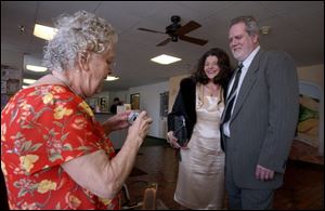 Elsie Baltrip, left, takes a photograph of Lisa and Aaron Simonton as he was honored at the Monroe Senior Center.
