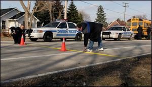 Police investigate the scene where the boy was struck by a car that allegedly drove past his bus  warning lights.
