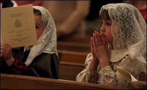 Margot Maxon, 6, and Hayden Maxon, 8, participate in the Mass for Pope John II at Rosary Cathedral in Toledo.

