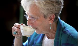 Mary Ann Wilkins of Elmore sips her tea before having her leaves read by Ellen Kraus. Ms. Kraus said she senses life trends and cycles by studying the leaves left in the cup.