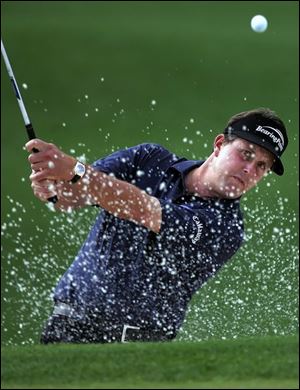 Phil Mickelson blasts from the sand on the second hole yesterday. He is 3-under par, but that's 10 shots off the lead.