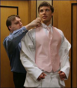Jeff Nowicki, left, manager of President Tuxedo fits a white tuxedo with pink vest for St. John's Jesuit High School senior Ted Heintschel.