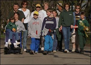 Shelly Knapik, far left, holds her daughter, Casey, 6, in a wheelchair as it is pushed along the route by her husband, Bob.