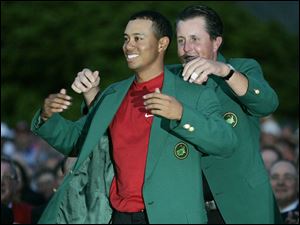 Last year's champion, Phil Mickelson, puts the fourth green jacket on Tiger Woods. Mickelson shot 74 yesterday.
