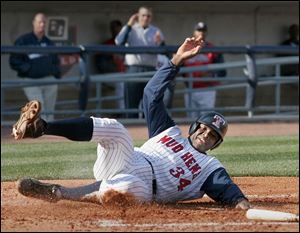 Catcher Sandy Martinez slides across the plate with the Mud Hens' second run last night in the home opener at Fifth Third Field. The Hens, who lead the International League's West Division with a 7-1 record, got good pitching, solid defense and productive offense to win easily before a record crowd of 12,500. Martinez got just one of the Hens' 12 hits, but in addition to scoring this run had two runs batted in.