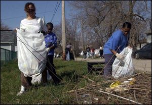 Melissa Awls, left, Angela Foreman, and Tracy Stubblefield clean an alley between Summit Street and Greenbelt Parkway. 