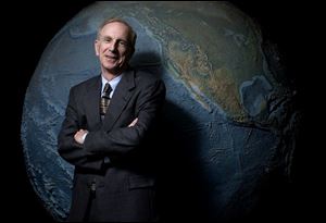 Elliot Tramer stands before a large globe inside the Carlson Library at the University of Toledo. The professor of ecology helped co-organize the first Earth Day event at the university in 1970. The annual commemoration has evolved significantly in Toledo, the nation, and the world in the years since. 