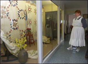 NBR wolcott22p 2 Wolcott House tour guide Sandy Miller looks at historic quilts, part of the Stitches through Time exhibit, while waiting for a tour to arrive, April 22, 2005. The Blade/Lori King