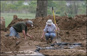 Gary Borton and Patty Croninger look for evidence of grave sites at the former Miami Children's Home in Maumee last week.