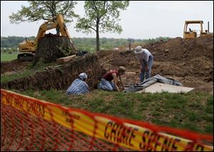 Kate Hayfield, left, Rachel Davies, and Patty Croninger work at uncovering the remains of a grave site at the former Miami Children's Home on River Road last week.