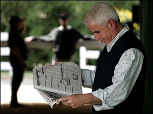 Trainer Nick Zito reads the horse racing news as he awaits the arrival at Pimlico of High Fly, Noble Causeway and Sun King.
