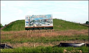The only indication of progress at the Maumee site is a grass-covered mound, behind a sign promoting a 2005 opening. 