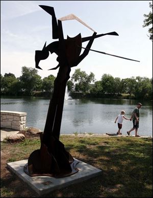 Gary Olson of Perrysburg and his son, Zach, 6, enjoy Williams Park near  Hair Streak,  a sculpture by John Parker.
