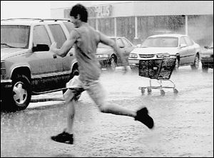 A shopper makes a mad dash for his car in a parking lot at Lewis Avenue and Alexis Road
during one of the downpours that have swept through the area intermittently in the last
several days. The forecast calls for partly sunny skies and more pleasant conditions with
less humidity at least through Monday. 