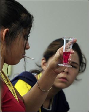 From left, Lucy Gutierrez, 15, of Fremont and Kalie Salas, 14, of Toledo mix chemicals to create a gel during a program at the University of Toledo, 'UT Empieza Contigo,' - Spanish for 'UT Starts With You.' The program is aimed at young migrant workers and other Latino youths.