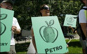 Lakshmi Satya, center, of Celina, Ohio, protests in Columbus at a seminar for the Ohio GOP. The protesters are calling state Auditor Jim Petro and fund-raiser Tom Noe 'GOP bad apples.'
