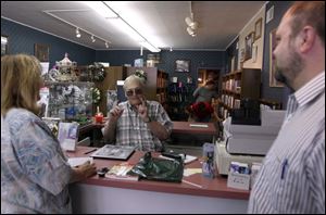 Jerry Matheny, owner of Books, Brass, & Candles with his wife Sandy, said he will miss talking with customers, as he is here with Cecelia Yackee Nartker and pastor Scott Silcox.