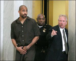 Jamie Madrigal is escorted by Mark Lair, right, director of court security, and deputy Willie Gulley, for his arraignment.