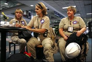 Members of the Toledo Area Disaster Medical Assistance Team, from left, Jackie Hill, Kathy D'Amore, and Dawn Rogers, wait at Toledo Express Airport for their flight toward the storm zone.