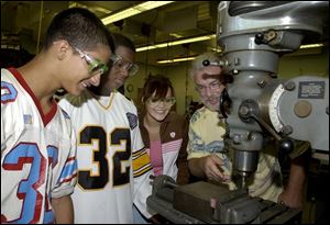 Bowsher students, from left, Troy Rios, Marion Reid, and
Georgianna Whitely paid an extra fee for a metal technology
class, where Dave Fink teaches them about a drill press.
