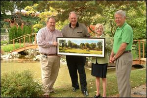 Mark Reilly, left, and Nancy Reilly with a painting by John
Wurzell, center. The couple purchased the work at the Hidden Garden Party at Schedel Arboretum & Gardens.