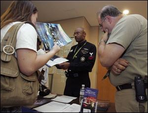 Sarah Melin, 16, left, and her father, Steve Melin, get information from Naval Reserves PO 2nd Class Kevin E. Crumble at Bowsher High School. Parents and Toledo Public Schools students not interested in the service can opt out of giving the military access to their personal data, but because of the No Child Left Behind Act, there are consequences. So far, 221 students have opted out, the district said.