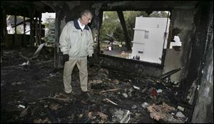 Lou Ratajski, owner of Jim and Lou's Bar, examines the damage from a fire ignited during the rioting on Saturday.