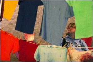 Tracy Scott, a junior at the University of Toledo, takes in the messages from victims of domestic violence written on T-shirts that hang from a clothesline. The display, located on UT's campus, is one event during Domestic Violence Awareness Month. In the last several months, Lucas County has experienced nine cases of domestic-violence related murder-suicides, officials say.