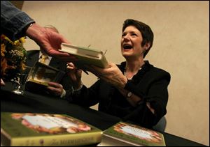 Sue Monk Kidd, author of 'The Secret Life of Bees' and 'The Mermaid Chair,' hands a book to a fan at the Stranahan Theater.