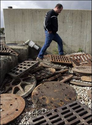 Sewer department foreman Bill Wiciak steps between sewer grates. About 122 such grates have been plucked from city streets, many in West Toledo, during the last four months.
