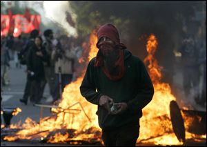 ASSOCIATED PRESS A masked protester carries stones during a march against the presence of President Bush in Mar del Plata, Argentina.