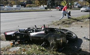 Charles Dreier of Milbury, in Ottawa County, retrieves pieces of the wreckage of his car after it collided with a motorcycle on Alexis Road at Harvest Lane yesterday. The motorcyclist, Joel Green, 39 of Monclova Township, was admitted in fair condition to Toledo Hospital. Mr. Green was thrown from his motorcycle, but was able to get up and walk back to his overturned bike. Police said Mr. Dreier, 51, who was not hurt, was at fault.