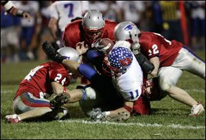 Wayne Trace s Jay Priest (11) is tackled by Patrick Henry s Kyle Brubaker (24), Cole Reese, Tom Busch (12) and an unidentified player (bottom).
