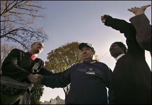 The Rev. Will Stuart, left, North Toledo resident John Szych, and the Rev. Stephen Ward pray together outside Mr. Szych's Bronson Avenue house, which was damaged in the Oct. 15 riot.