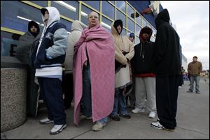 Jim McCree, wrapped in a blanket to keep warm, waits with about 40 others for the Toys R Us on Monroe Street to open.
