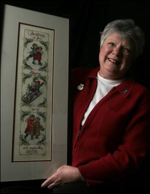 Sue Crescitelli holds a cross-stitch piece her late sister gave her as a gift while recovering from surgery and chemotherapy.