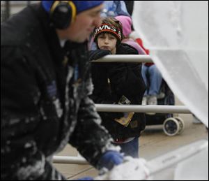 Pete Rodriguez, 8, doesn't mind the ice shavings as he leans in for a close look as Chad Hartson works his chain-saw magic.