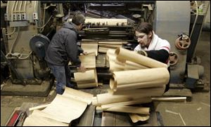 Matt Adelman, left, and Ed Hensley gather basketmaking material from a lathe that peels a long in the workshop of the Berlin Fruit Box Co. in Berlin Heights, Ohio.