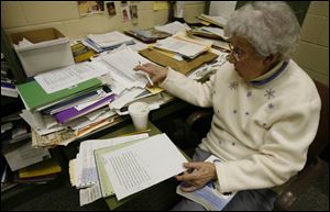 In her office, Louisa Strock sifts through student papers, looking for errant punctuation marks and other mistakes.