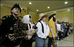Jameson Hicks, 9, left, dressed as Commodore Oliver Hazard Perry, holds a model of Perry's flagship, Lawrence. To the right are classmates at Aurora Academy also dressed as heroes to retell 23 stories of extraordinary Ohioans.