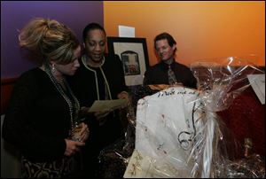 AUCTION ACTION: Valerie Suelzer, left, and Del Urolia scan the list of auction items during the benefit for the Fair Housing Center.