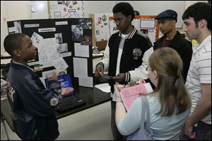 St. John's Jesuit High School's Jharad Davis, Ormand Saunders II, and James Johnson, from left, explain their project to judges Katie Green and Charles Disantis, far right, at the 15th annual History Day Competition, which was at the University of Toledo.