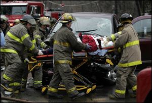 Firefi ghters remove a victim from a vehicle that was involved in a collision with a pickup on Secor. One person died and two were transported to Toledo Hospital in yesterday s accident.

