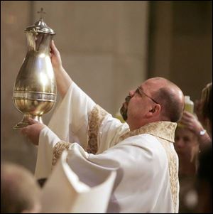 Deacon Victor DeFilippis of St. Rose Church, Perrysburg, presents the Oil of Catechumens for blessing.

