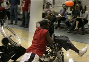Eric Jackson springs from his wheelchair to tackle UT wide receiver Andrew Hawkins in the end zone at last night's game. Red-shirted Crash players take on the University of Toledo football team on campus in a wheelchair football contest.