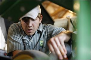 Michael Schrock, 18, checks out the John Deere no-till drill he uses on his soybean patch in Clinton Township.