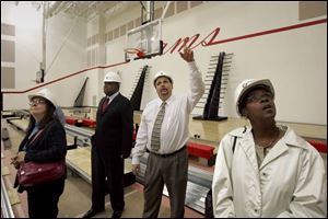 Principal Tony Brashear explains the features of one of the school s two gymnasiums to committee member Bonita Johnson, right. School leaders yesterday toured the nearly finished $33 million facility, which is adjacent to the existing Rogers, 5539 Nebraska Ave. 