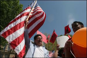 Fernando Mendoza waves a U.S. flag outside Rep. Paul Gillmor s office in Tiffin during a protest. 