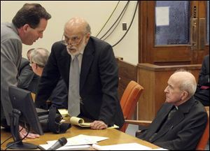 Defense attorneys John Thebes, left, and Alan Konop confer as the Rev. Gerald Robinson listens during his trial for murder.

