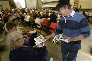 Cliff Moore, an Erie resident and fi refi ghter, passes out printouts of other developed intermodal rail yards during the meeting at the Erie Township Fire Department in Erie, Mich.
